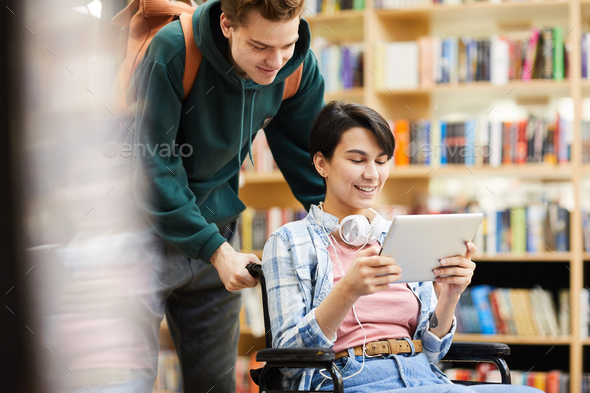 Cheerful girl in wheelchair using tablet - Stock Photo - Images