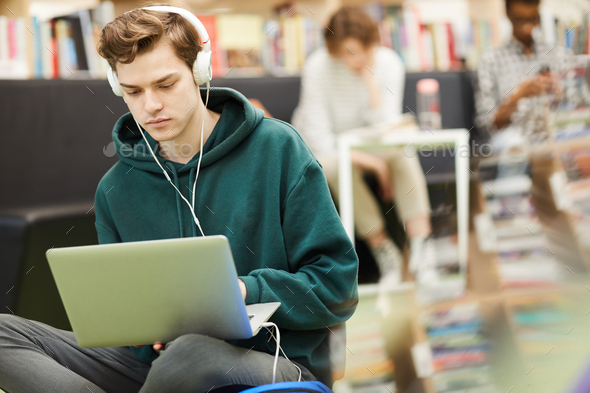 Hipster student using laptop in library - Stock Photo - Images