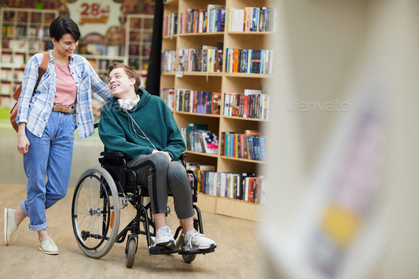 Disabled student visiting library with groupmate - Stock Photo - Images