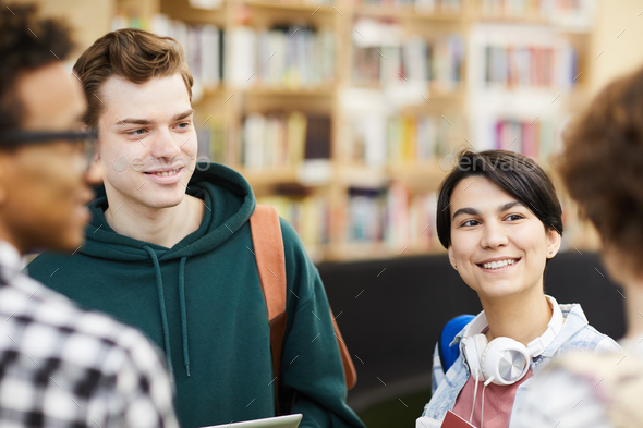 Positive students chatting in library - Stock Photo - Images