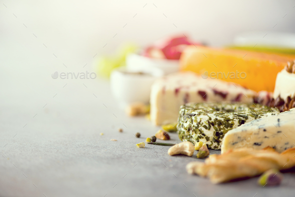 Assortment of hard, semi-soft and soft cheeses with olives, grissini bread sticks, capers, grape, on - Stock Photo - Images