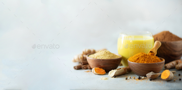 Healthy vegan turmeric latte or golden milk, turmeric root, ginger powder, black pepper over grey - Stock Photo - Images