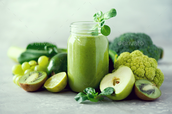 Glass jar mugs with green health smoothie, kale leaves, lime, apple, kiwi, grapes, banana, avocado - Stock Photo - Images