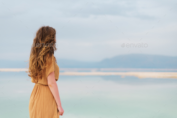 Young girl with shining blonde hair goes to seaside, Dead Sea beach. Banner. Travel, summer vacation - Stock Photo - Images