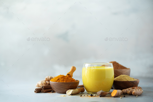 Ingredients for turmeric latte. Turmeric powder, curcuma root, cinnamon, ginger over grey background - Stock Photo - Images