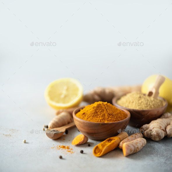 Ingredients for turmeric latte. Turmeric powder, curcuma root, cinnamon, ginger over grey background - Stock Photo - Images