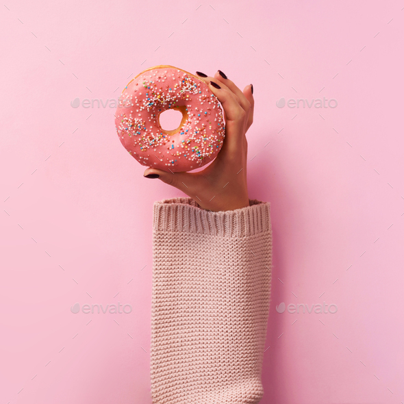 Female hands holding donut over pink background. Top view, flat lay. Sweet, dessert, diet concept - Stock Photo - Images