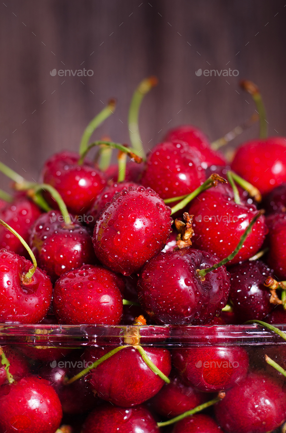 Sweet red cherries in glass bowl on dark wooden backgound with copy space. Summer and harvest - Stock Photo - Images