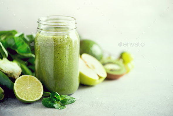 Glass jar mugs with green health smoothie, kale leaves, lime, apple, kiwi, grapes, banana, avocado - Stock Photo - Images