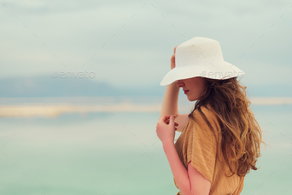 Young girl with shining blonde hair goes to seaside, Dead Sea beach. Banner. Travel, summer vacation - Stock Photo - Images