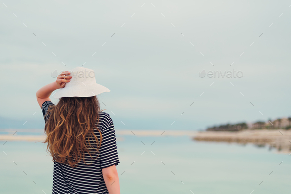 Young girl with shining blonde hair goes to seaside, Dead Sea beach. Travel, summer vacation - Stock Photo - Images
