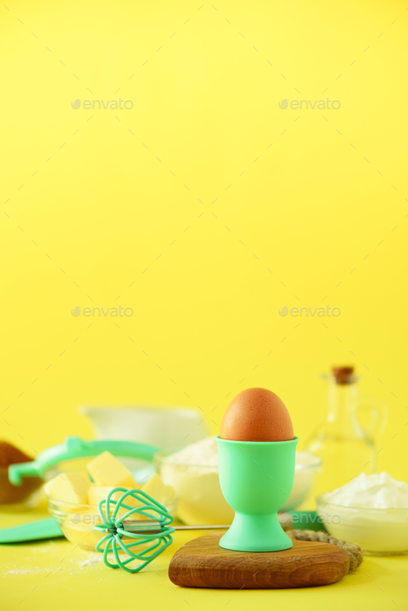 Healthy baking ingredients - butter, sugar, flour, eggs, oil, spoon, brush, whisk, milk over yellow - Stock Photo - Images