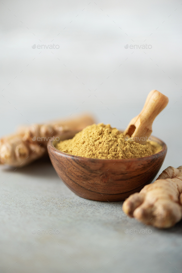 Ginger root and ginger powder in wooden bowl over grey concrete background with copy space. Immune - Stock Photo - Images