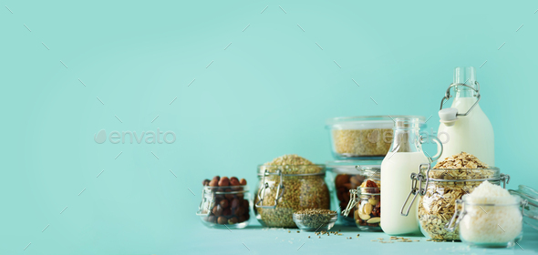 Glass bottles of vegan plant milk and almonds, nuts, coconut, hemp seed milk on blue background - Stock Photo - Images