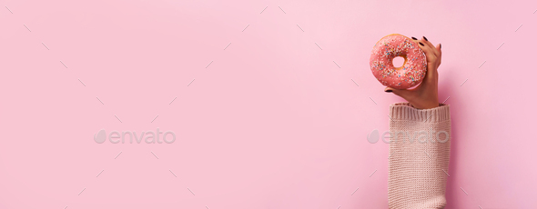 Female hands holding donut over pink background. Top view, flat lay. Sweet, dessert, diet concept - Stock Photo - Images