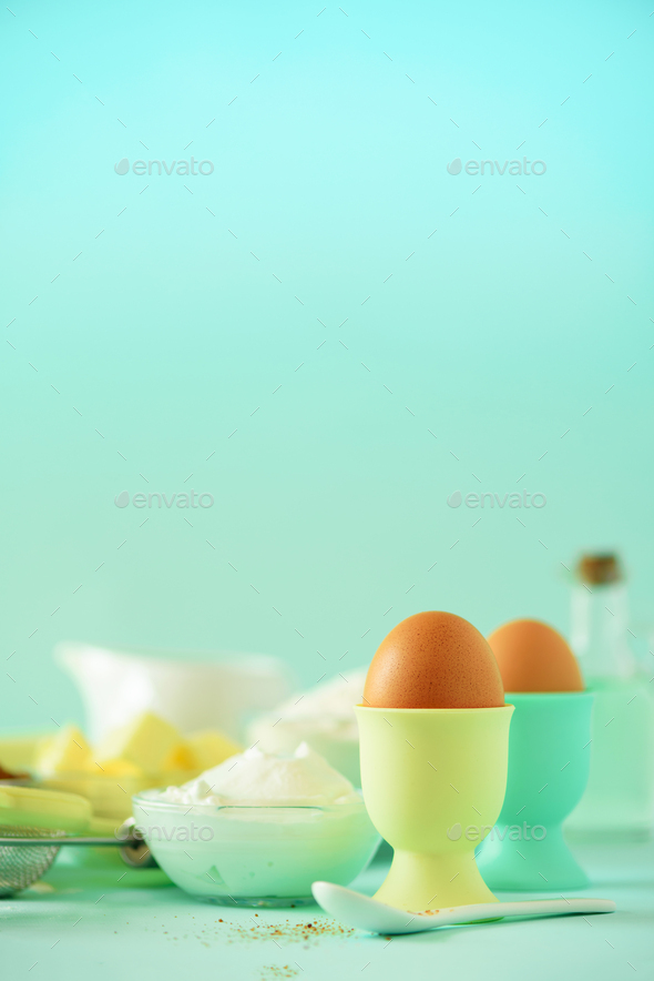 Healthy baking ingredients - butter, sugar, flour, eggs, oil, spoon, brush, whisk, milk over blue - Stock Photo - Images