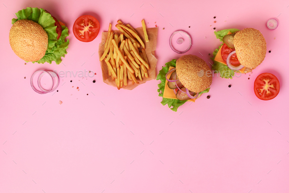 Tasty burgers with beef, tomato, cheese, onion, cucumber and lettuce on pink background. Top view - Stock Photo - Images