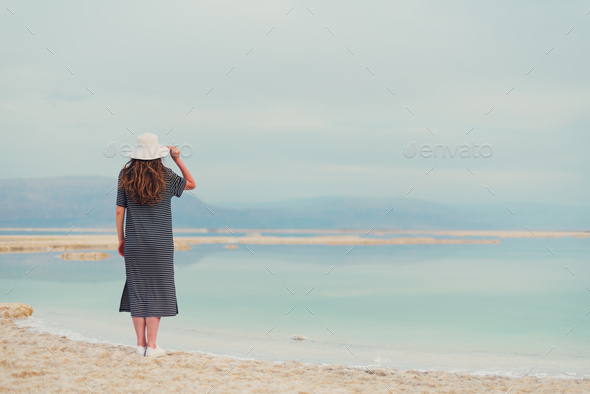 Young girl with shining blonde hair goes to seaside, Dead Sea beach. Travel, summer vacation - Stock Photo - Images