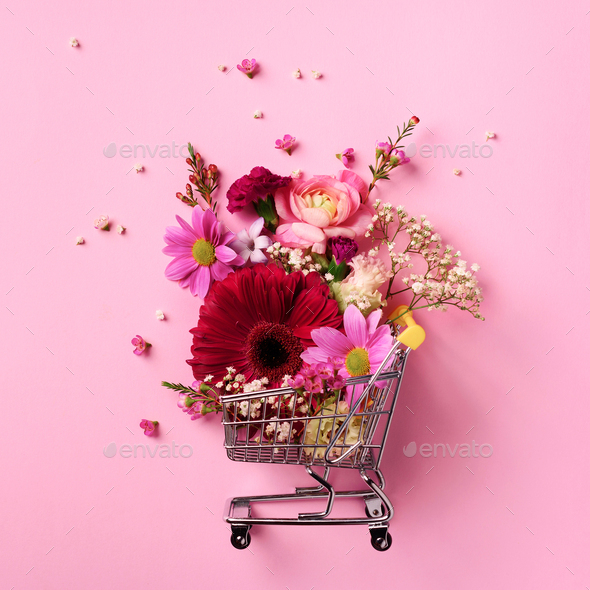 Shopping trolley with flowers on pink punchy pastel background. Banner with copy space. Top view - Stock Photo - Images