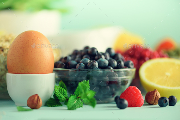 Breakfast served with soft boiled egg, oat flakes, nuts, fruits, berries, milk, yogurt, orange - Stock Photo - Images