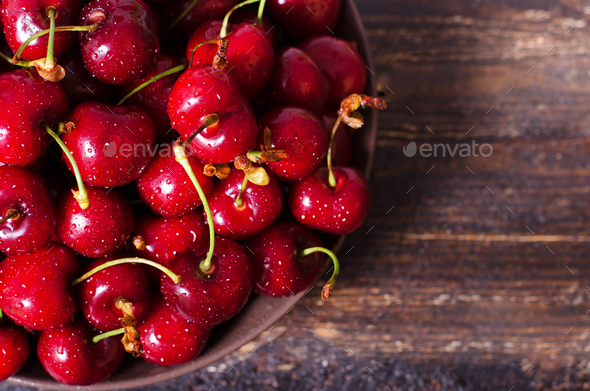 Fresh cherries in plate on dark wooden background with copy space. Summer and harvest concept - Stock Photo - Images