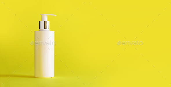 White bottle of moisturizing lotion on yellow background with copy space. Minimalism style. Skin - Stock Photo - Images