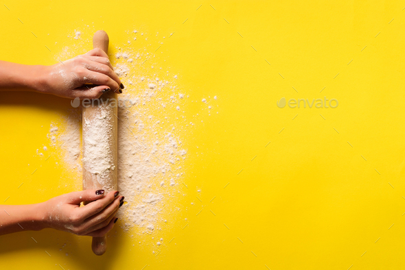 Girl hands keep rolling pin with flour on yellow background. Bake menu, recipe, homemade pastry - Stock Photo - Images