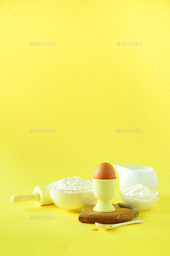 Healthy baking ingredients - butter, sugar, flour, eggs, oil, spoon, brush, whisk, milk over yellow - Stock Photo - Images
