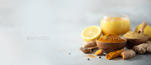 Healthy vegan turmeric latte or golden milk, turmeric root, ginger powder, black pepper over grey - Stock Photo - Images