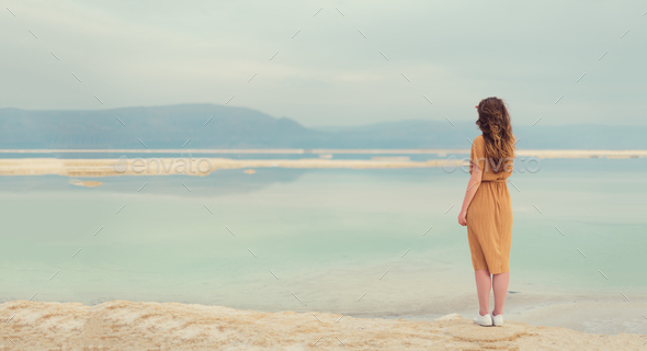 Back view of stylish girl wearing dress on seaside, Dead Sea beach. Travel, summer vacation, holiday - Stock Photo - Images