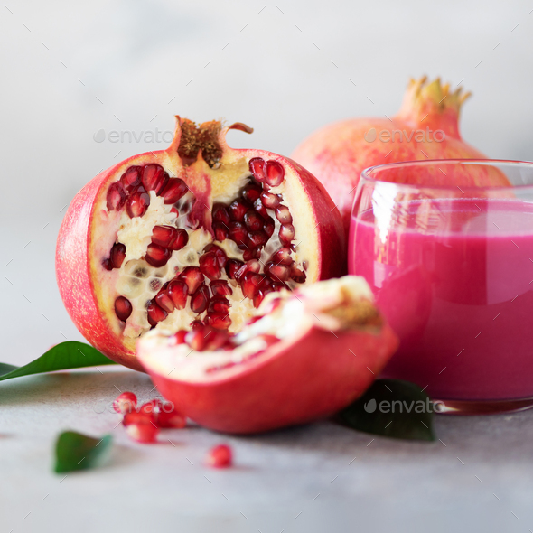 Glass of pomegranate juice with ripe pomegranate fruit on grey concrete background. Banner with copy - Stock Photo - Images