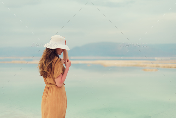 Young girl with shining blonde hair goes to seaside, Dead Sea beach. Banner. Travel, summer vacation - Stock Photo - Images