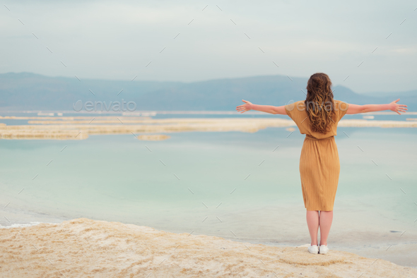 Young girl with shining blonde hair goes to seaside, Dead Sea beach. Banner. Travel, summer vacation - Stock Photo - Images