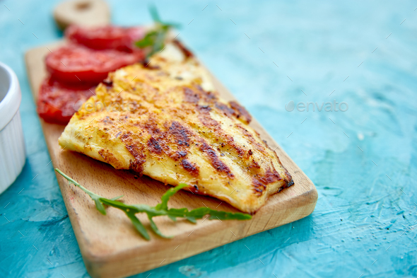 Grilled pike fillet with tomatoes on wooden board - Stock Photo - Images