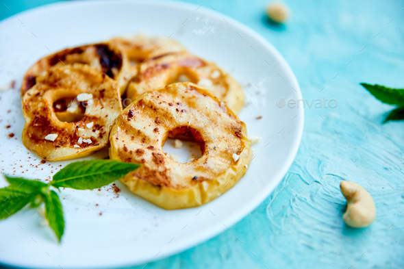Grilled apples with cinamon on white plate on blue background. - Stock Photo - Images