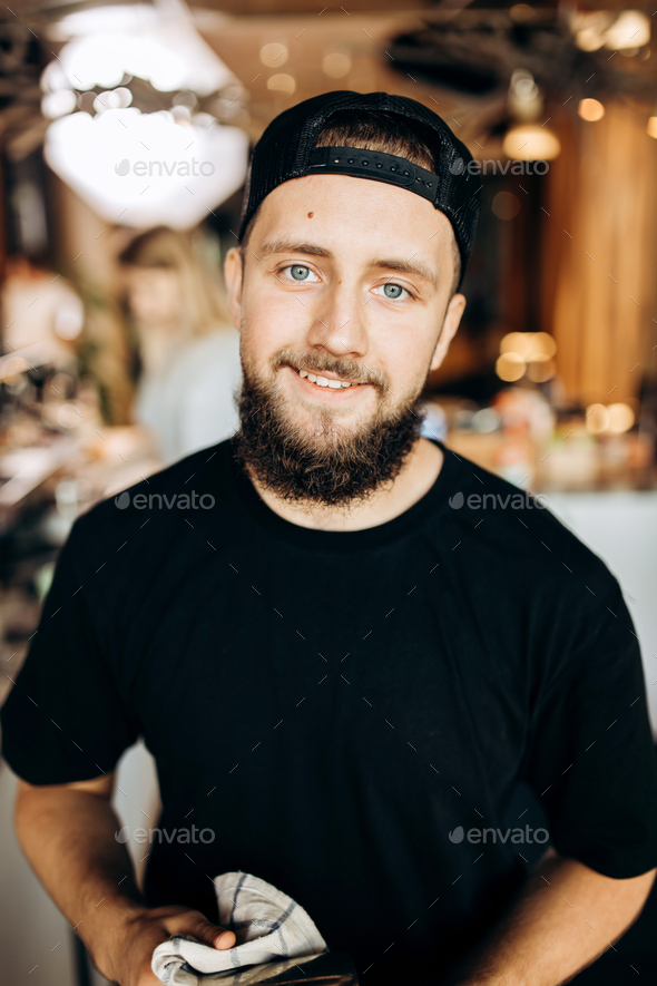 A handsome smiling youthful stylish man with beard,dressed in casual outfit,stands and looks at the - Stock Photo - Images