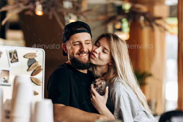 Two young smiling people,a blonde girl and man with beard.dressed in casual outfit, stand next to - Stock Photo - Images