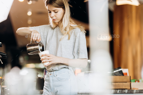 A good looking slim blonde with long hair,dressed in casual outfit,is cooking coffee in a modern - Stock Photo - Images