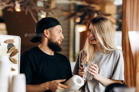 Two young smiling people,a blonde girl and man with beard.dressed in casual outfit, stand next to - Stock Photo - Images