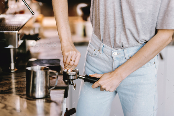 A good looking slim blonde with long hair,dressed in casual outfit,is cooking coffee in a modern - Stock Photo - Images