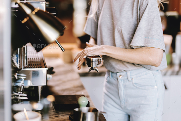 A good looking slim blonde with long hair,dressed in casual outfit,is cooking coffee in a modern - Stock Photo - Images