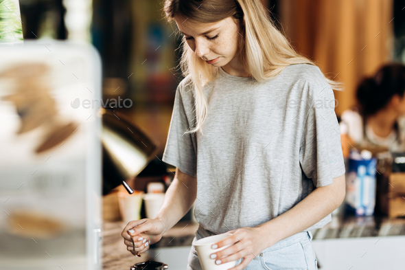 A good looking slim blonde with long hair,dressed in casual outfit,is cooking coffee in a modern - Stock Photo - Images