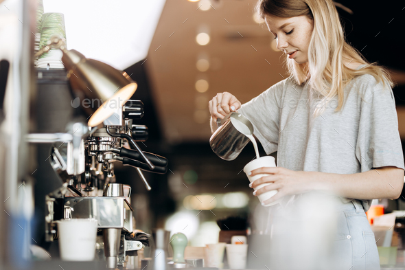 A good looking slim blonde with long hair,dressed in casual outfit,is cooking coffee in a modern - Stock Photo - Images