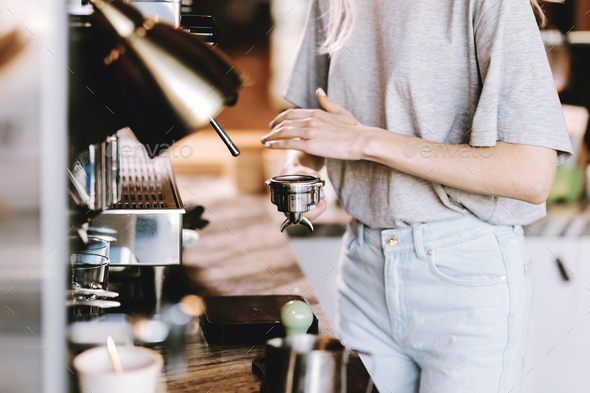 A good looking slim blonde with long hair,dressed in casual outfit,is cooking coffee in a modern - Stock Photo - Images
