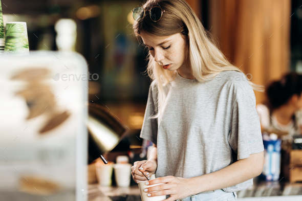 A good looking slim blonde with long hair,dressed in casual outfit,is cooking coffee in a modern - Stock Photo - Images