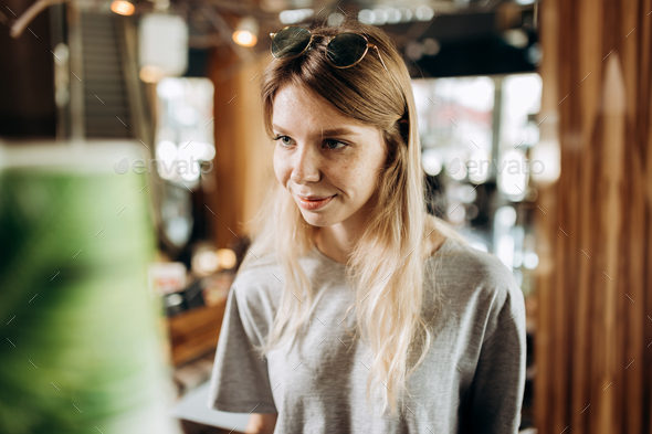 A good looking youthful slim girls,wearing casual style, is standing next to the coffee machine and - Stock Photo - Images