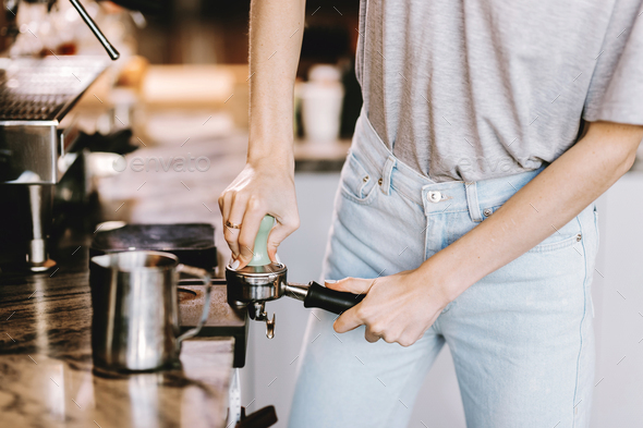 A good looking slim blonde with long hair,dressed in casual outfit,is cooking coffee in a modern - Stock Photo - Images