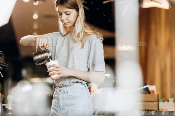A good looking slim blonde with long hair,dressed in casual outfit,is cooking coffee in a modern - Stock Photo - Images