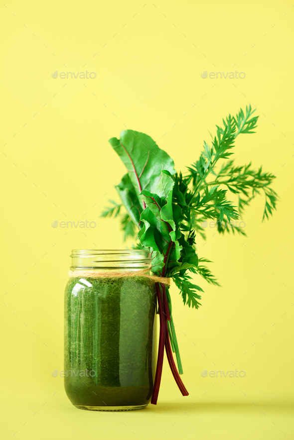 Smoothie with beet greens and carrot tops on yellow background, copy space. Summer vegan food - Stock Photo - Images
