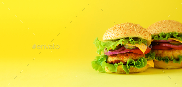 Unhealthy burgers with beef, cheese, lettuce, onion, tomatoes on yellow background. Take away meal - Stock Photo - Images